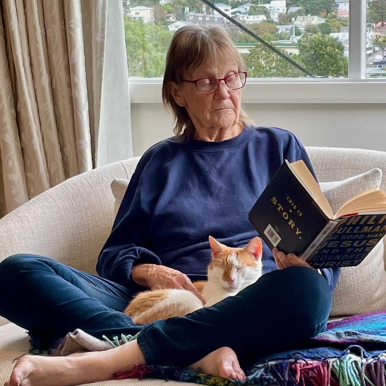 Pam reading with a cat asleep on her lap
